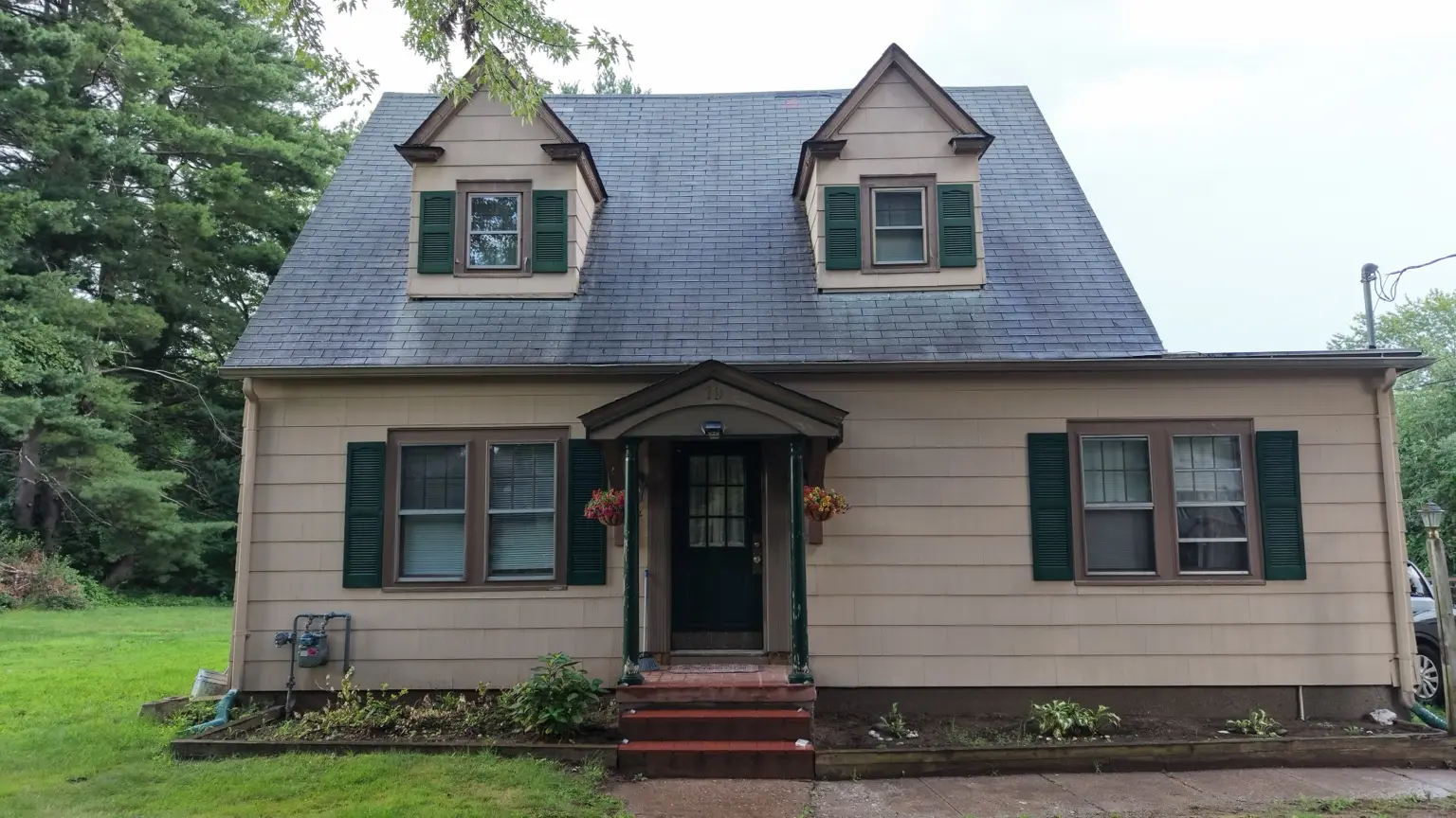 The residence before roof replacement, with its steep front slope and two dormers.