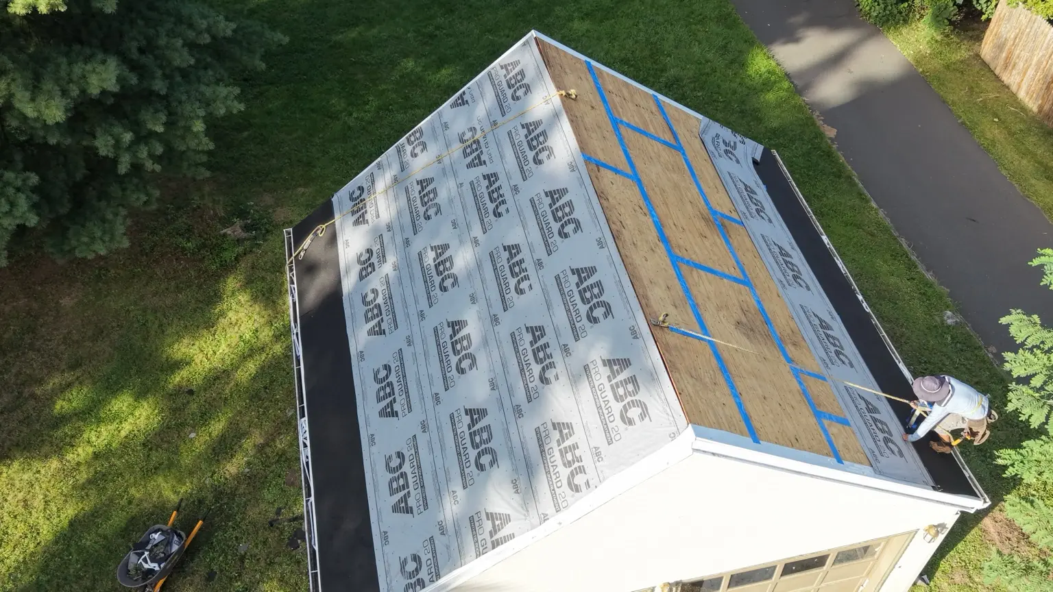 The detached garage during preparation, with seam tape and protective roof layers visible.
