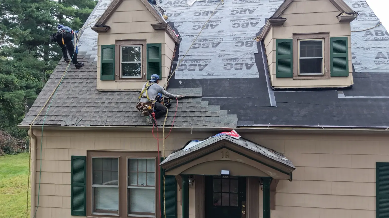 Shingle installation underway around the residence’s front dormers.
