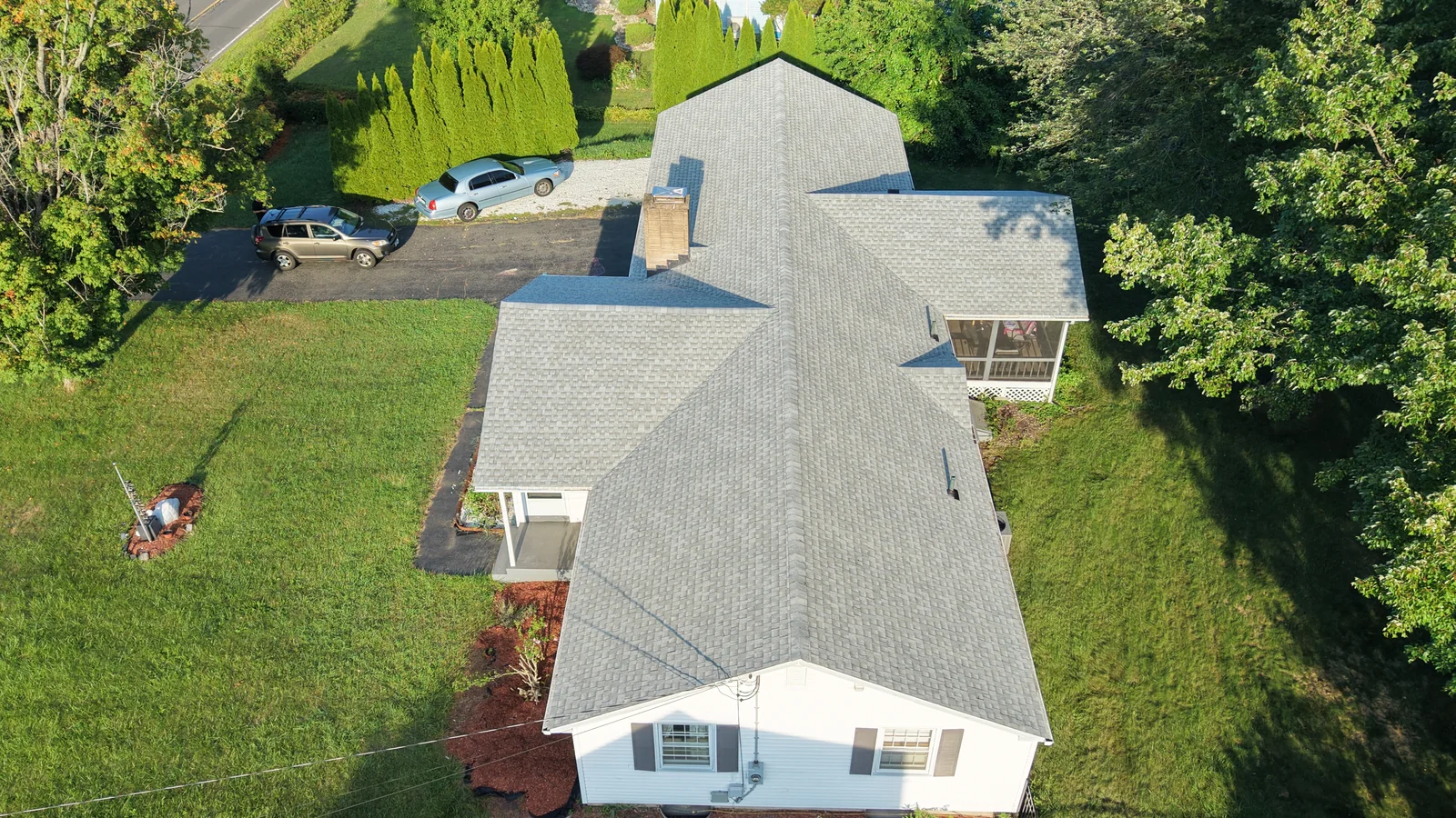 A drone view of a shingle roof on a white home with several roof sections